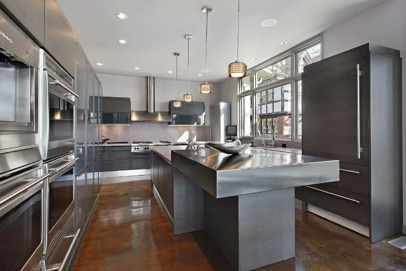 Luxury kitchen with stainless steel countertops, pendant lighting, and professional-grade appliances by Amerbuild
