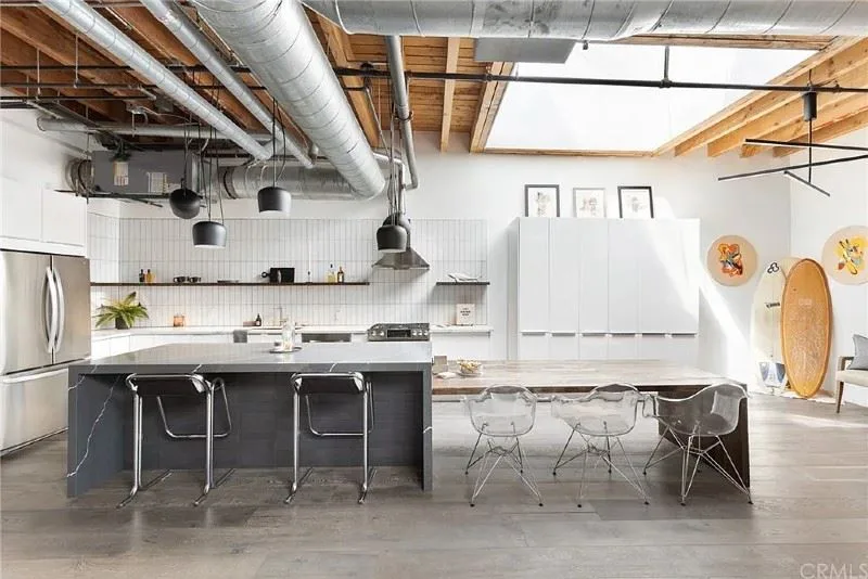 Open-concept industrial kitchen remodel in Los Angeles with exposed beams, pendant lighting, and modern island seating
